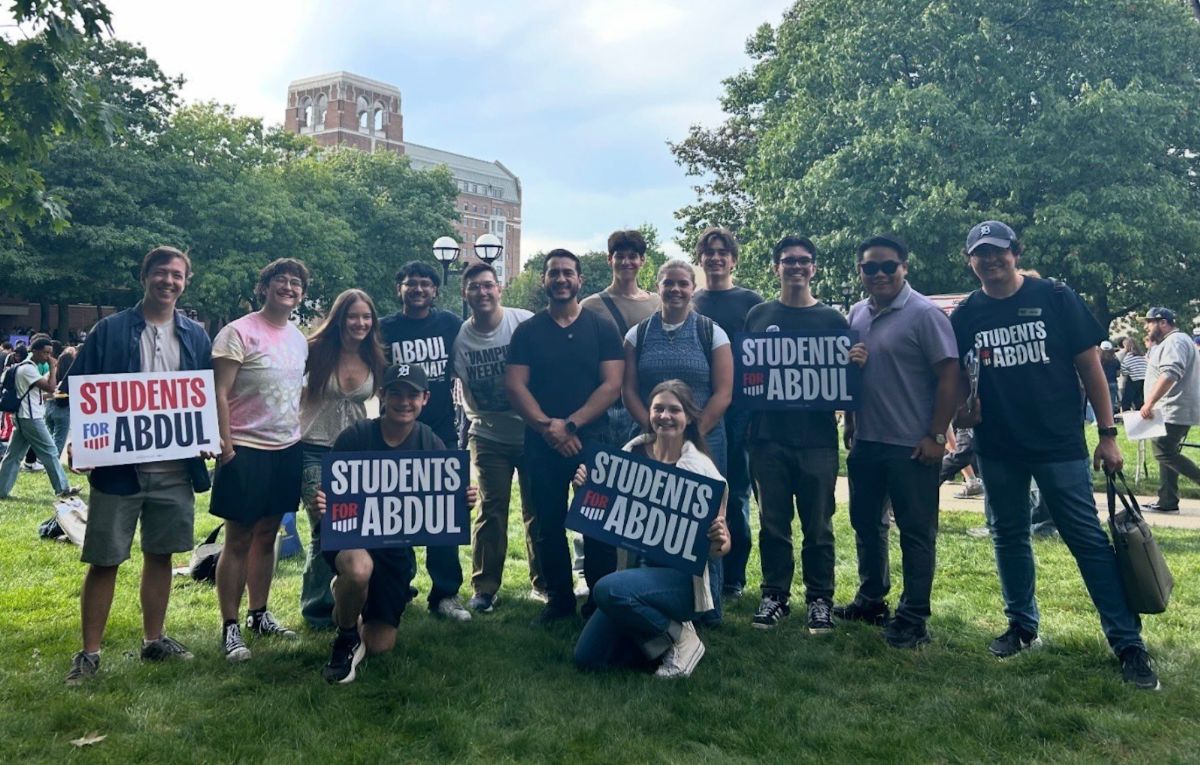 A group of students smiling with Abdul on campus.
