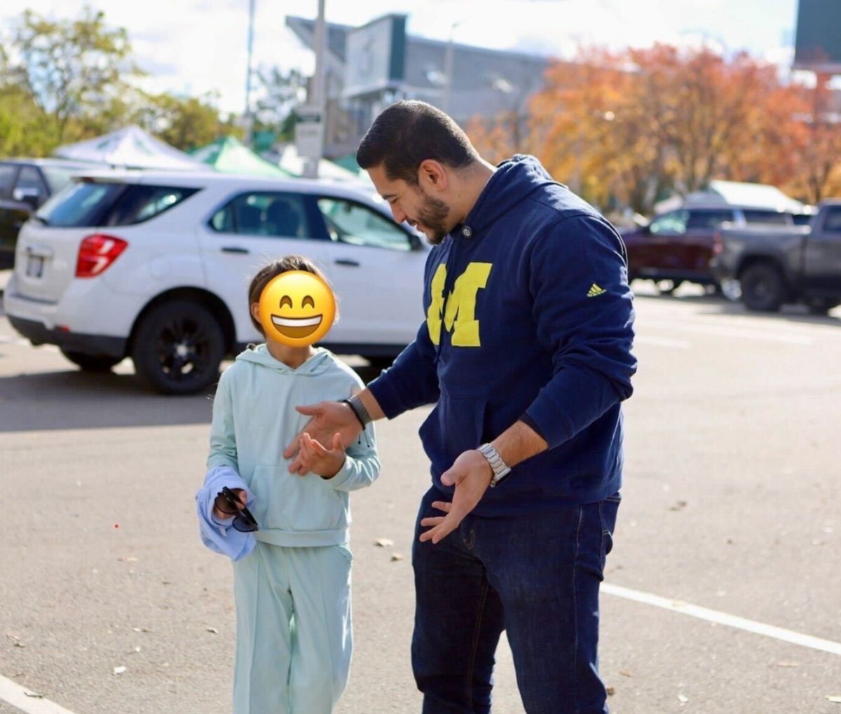 Abdul and one of his daughters smiling together. Abdul is wearing a University of Michigan hoodie.