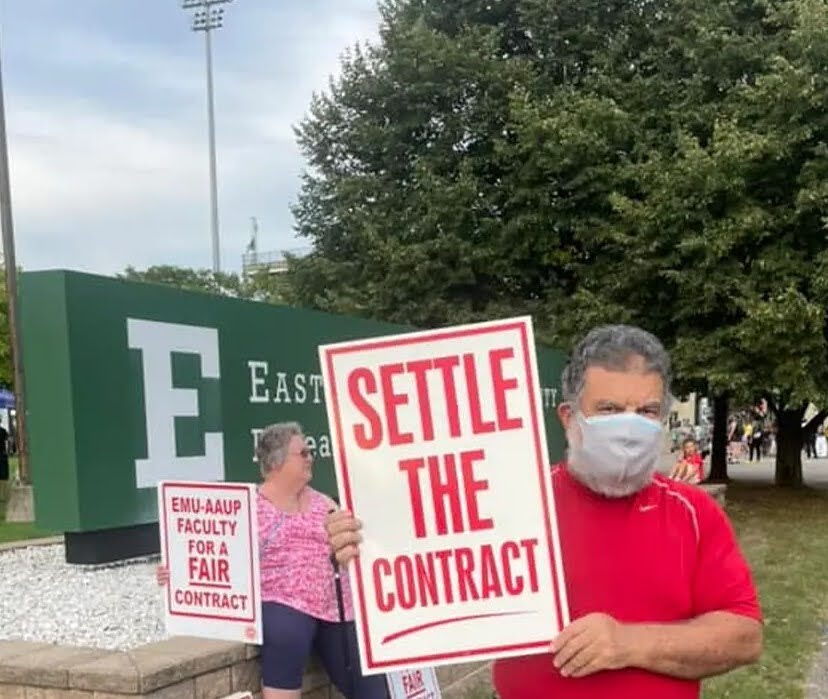 Prof. Mohamed on strike. He's holding up a sign that says 'SETTLE THE CONTRACT'